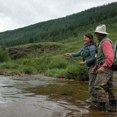 Young woman and older man fly fishing in a river