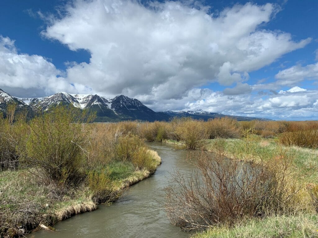 Clouds, snow capped mountains, stream in Red Rocks Lakes Wildlife Refuge