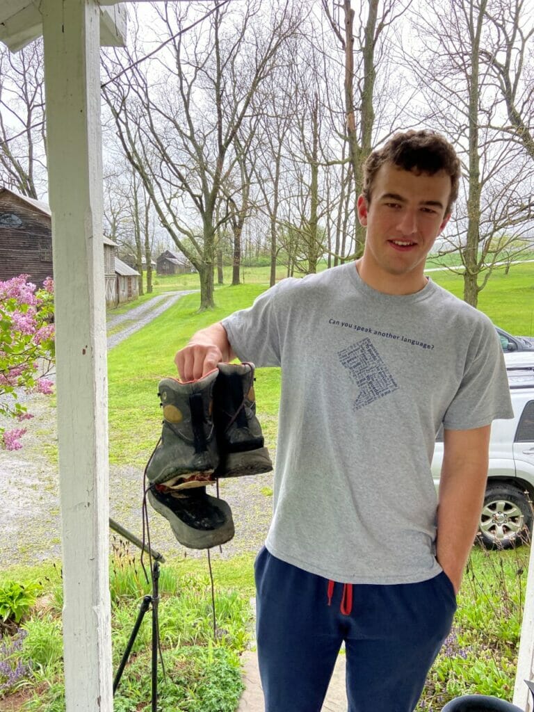Young man holds up boots with sole falling off