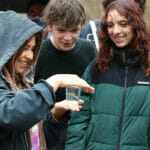 On a rainy day students hold a jar containing a small fish