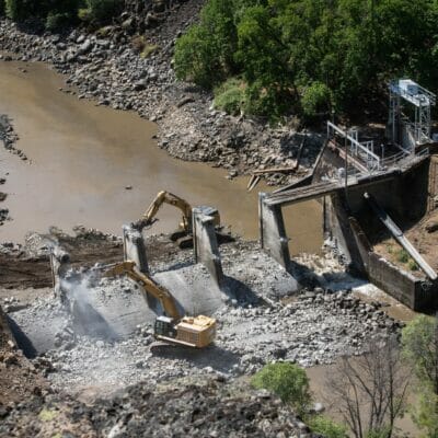 Areal view of cranes breaking a dam apart