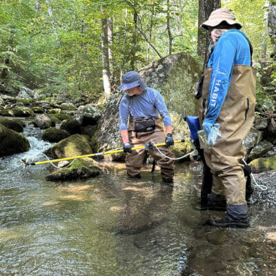 Two men with equipment in a stream